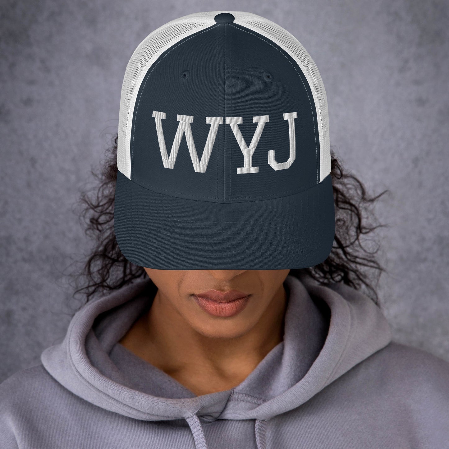 Woman wearing a WYJ trucker cap showing  the front of the hat